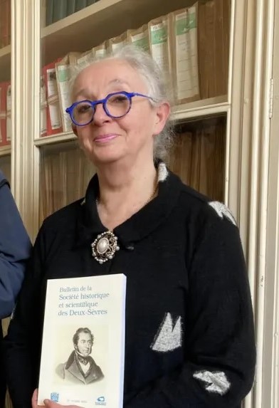SHSDS : Fabienne Texier. Dernière présidente de la Société historique et scientifique des Deux-Sèvres depuis 2022 devant la bibliothèque de la salle du Conseil d'administation de la sociétés